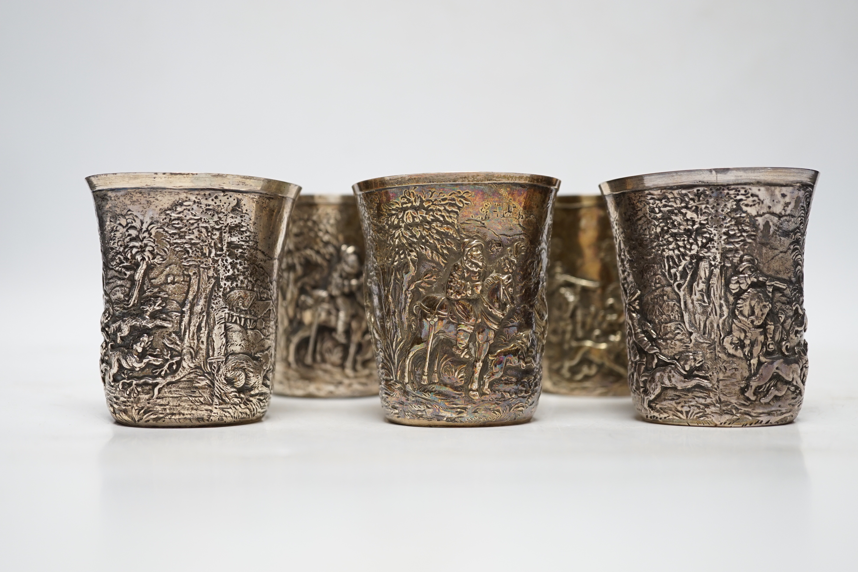 A set of five late 19th century German embossed 925 beakers, decorated with continuous hunting scenes, by Neresheimer Ludwig & Co, 67mm, 16.7oz
